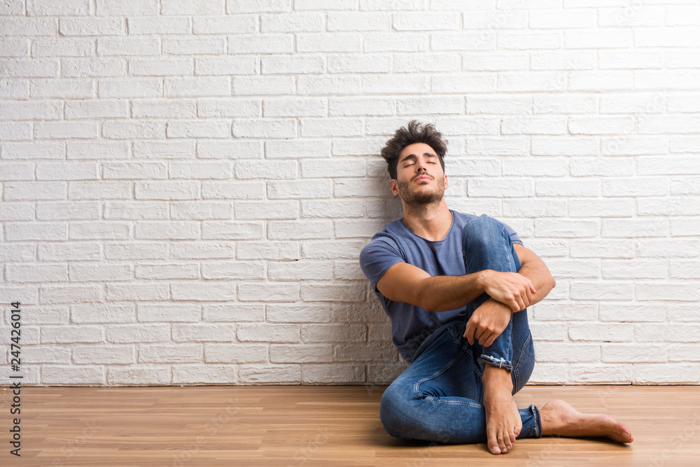 Young natural man sit on a wooden floor proud and confident, pointing fingers, example to follow, concept of satisfaction, arrogance and health