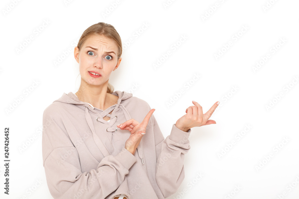 Portrait of happy surprised young woman model indicates with fore finger shows place for your advertisement or promotional text.