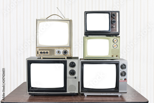 Five vintage televisions on old wood table with cut out screens