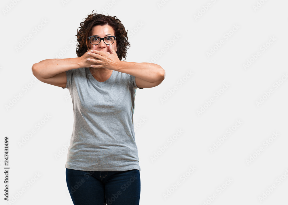 Middle aged woman covering mouth, symbol of silence and repression, trying not to say anything Middle aged woman covering mouth, symbol of silence and repression, trying not to say anything