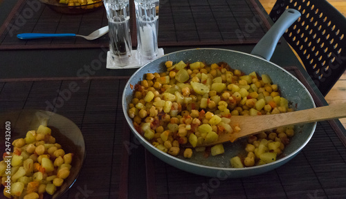 pan with chickpeas and potatoes traditional dish from canary island. 2 dishes with a blue spoon and black table with blach chairs