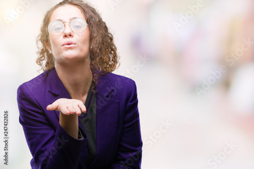 Young brunette student girl wearing school uniform and glasses over isolated background looking at the camera blowing a kiss with hand on air being lovely and sexy. Love expression.