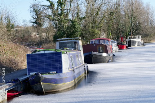 Boat mooring marina in winter snow and ice frozen water and wooden pier jetty at barge sailing club photo