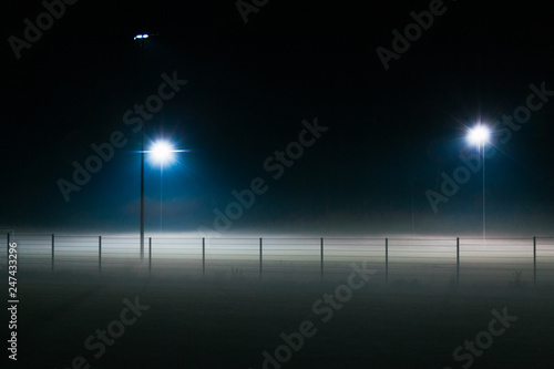 Lonely and mystic football field covered by fog at night