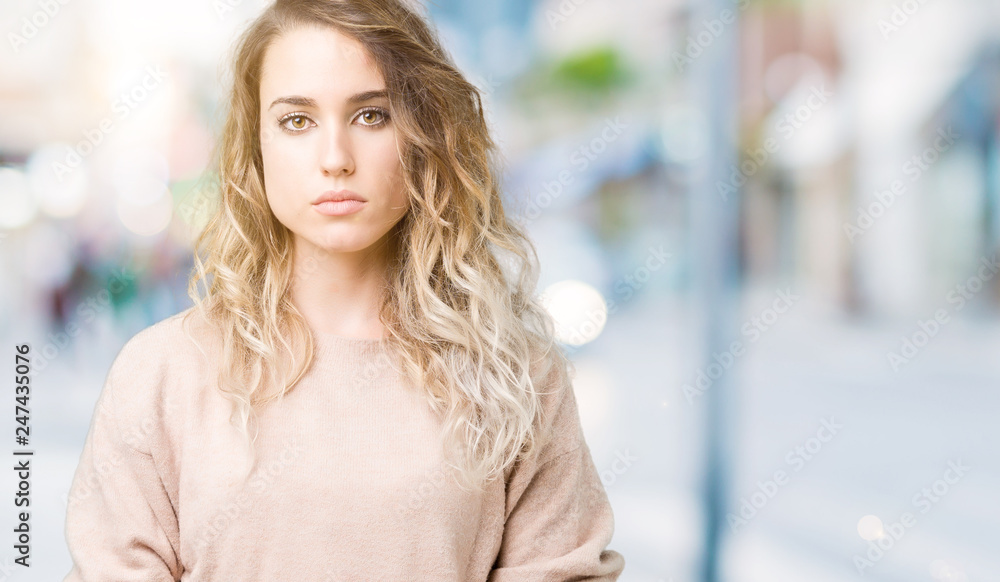 Beautiful young blonde woman wearing sweatershirt over isolated background Relaxed with serious expression on face. Simple and natural looking at the camera.