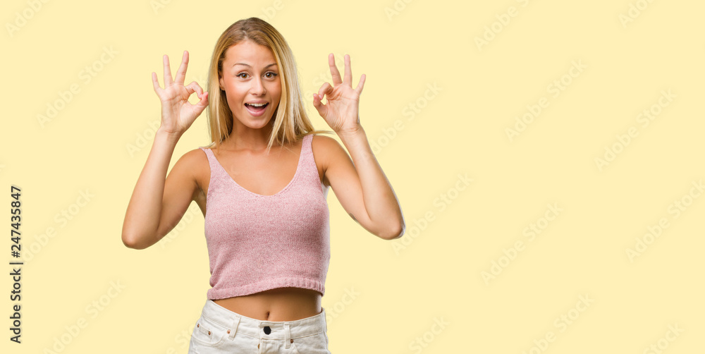 Portrait of young pretty blonde woman cheerful and confident doing ok gesture, excited and screaming, concept of approval and success Portrait of young pretty blonde woman cheerful and confident doing ok gesture, excited and screaming, concept of approval and success