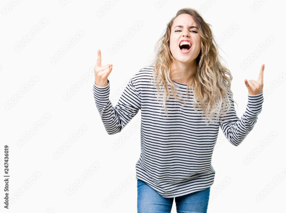 Beautiful young blonde woman wearing stripes sweater over isolated background shouting with crazy expression doing rock symbol with hands up. Music star. Heavy concept. Beautiful young blonde woman wearing stripes sweater over isolated background shouting with crazy expression doing rock symbol with hands up. Music star. Heavy concept.