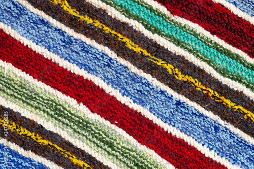 different colored stripes on the knitted fabric surface. background close-up of textiles retro rugs or rugs. the texture of the fabric is a combination with the geometry of the lines. handmade product