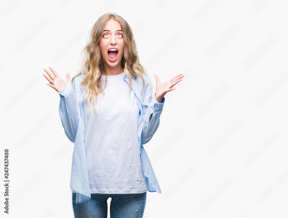 Beautiful young blonde woman over isolated background crazy and mad shouting and yelling with aggressive expression and arms raised. Frustration concept. Beautiful young blonde woman over isolated background crazy and mad shouting and yelling with aggressive expression and arms raised. Frustration concept.