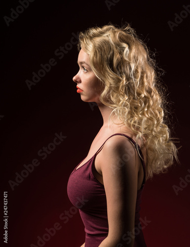 Beautiful woman with blonde long curly hair. Beauty portrait of modern fashion, red background.