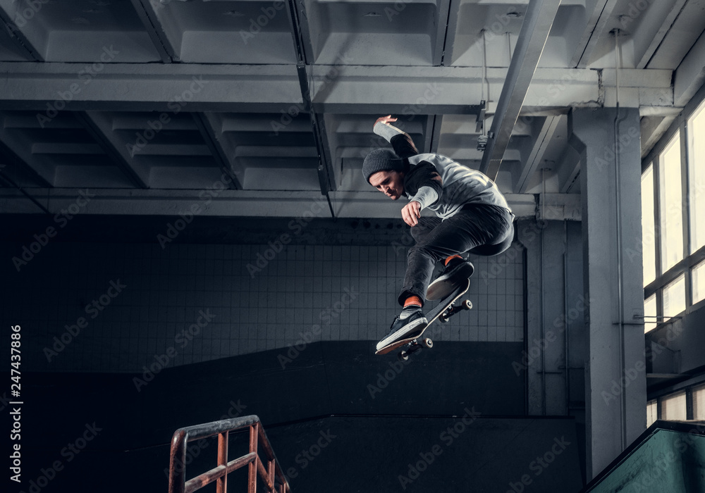 Skateboarder jumping high on mini ramp at skate park indoor. - obrazy, fototapety, plakaty 