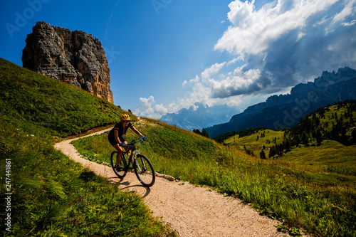 Couple cycling in Cortina d'Ampezzo, stunning Cinque Torri and Tofana in background. Woman and man riding MTB trail. South Tyrol province of Italy, Dolomites. © Gorilla