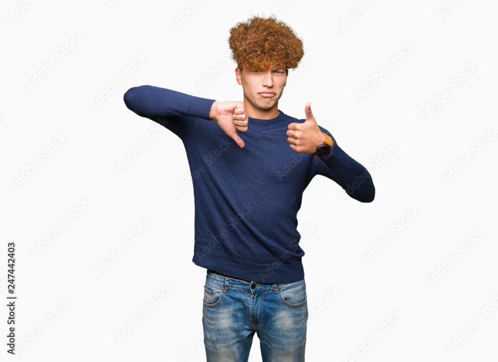 Young handsome man with afro hair Doing thumbs up and down, disagreement and agreement expression. Crazy conflict Young handsome man with afro hair Doing thumbs up and down, disagreement and agreement expression. Crazy conflict