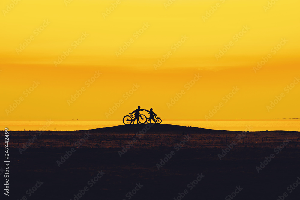 Silhouette friend and bike relaxing on sunset background