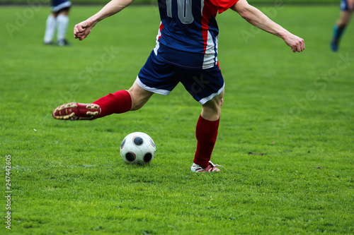 A detail picture of a footballer kicking the ball during the football game