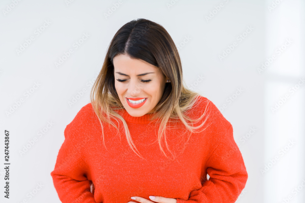 Young woman wearing casual red sweater over isolated background with hand on stomach because indigestion, painful illness feeling unwell. Ache concept. Young woman wearing casual red sweater over isolated background with hand on stomach because indigestion, painful illness feeling unwell. Ache concept.