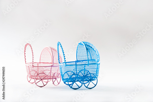 A miniature stroller for a child isolated on a white background. Two strollers for a boy and a girl on a white background. The concept of twins pink and blue, in vitro fertilization photo