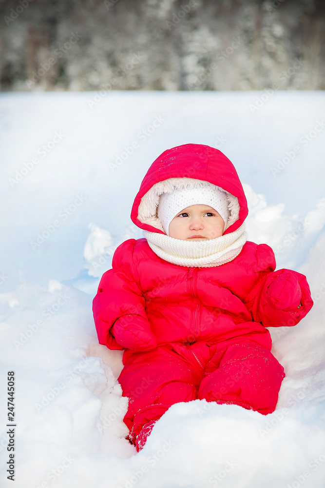 Little baby in a red jumpsuit posing in winter