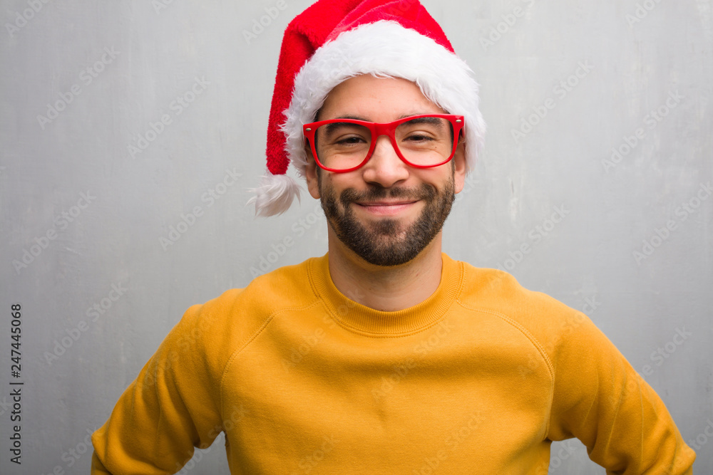 Young man celebrating christmas day holding gifts with hands on hips Young man celebrating christmas day holding gifts with hands on hips