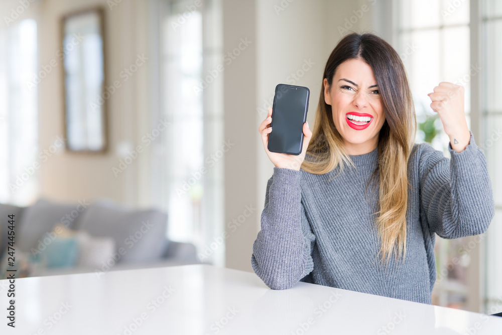Young beautiful woman showing smartphone screen at home annoyed and frustrated shouting with anger, crazy and yelling with raised hand, anger concept Young beautiful woman showing smartphone screen at home annoyed and frustrated shouting with anger, crazy and yelling with raised hand, anger concept