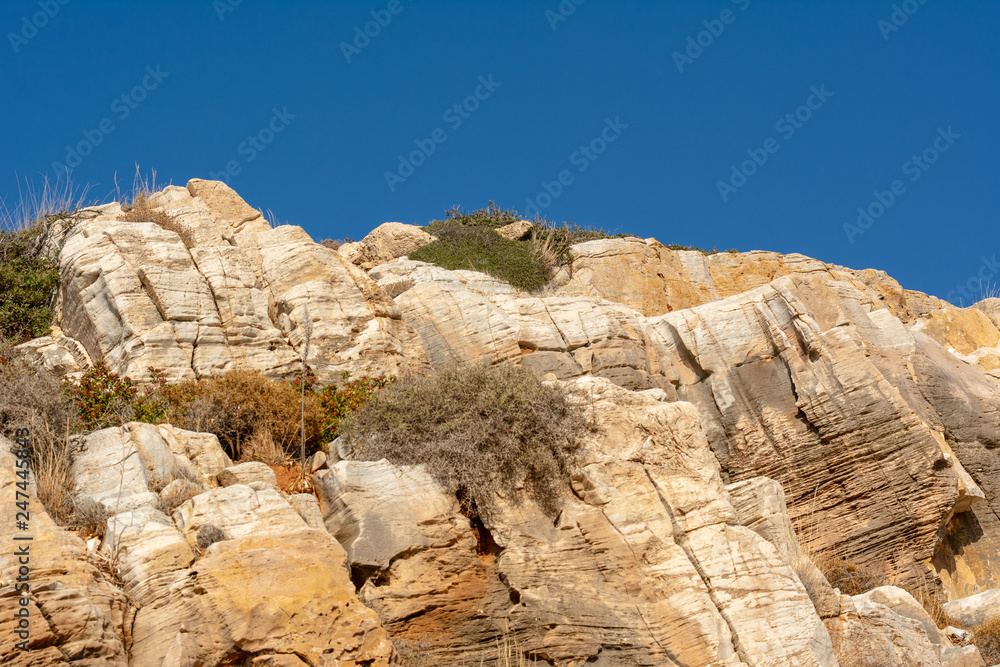 Natural texture of rocks against blue sky. Cracked and weathered natural stone background