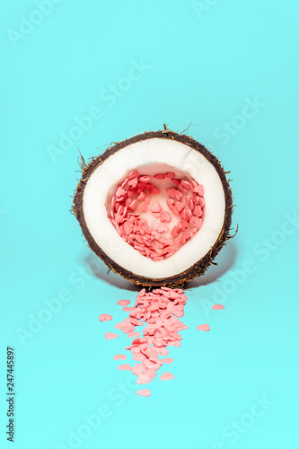 Love concept minimal. Bright colorful background with coconut and candy hearts in pink and turquoise colors. Valentine's day minimal concept. Contemporary art design, abstract minimalism