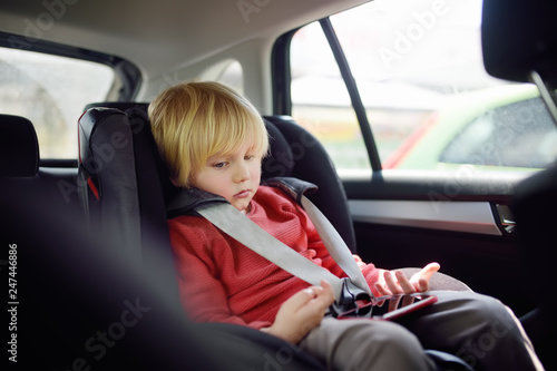 Portrait of a bored little boy sitting in a car seat. Safety of children.