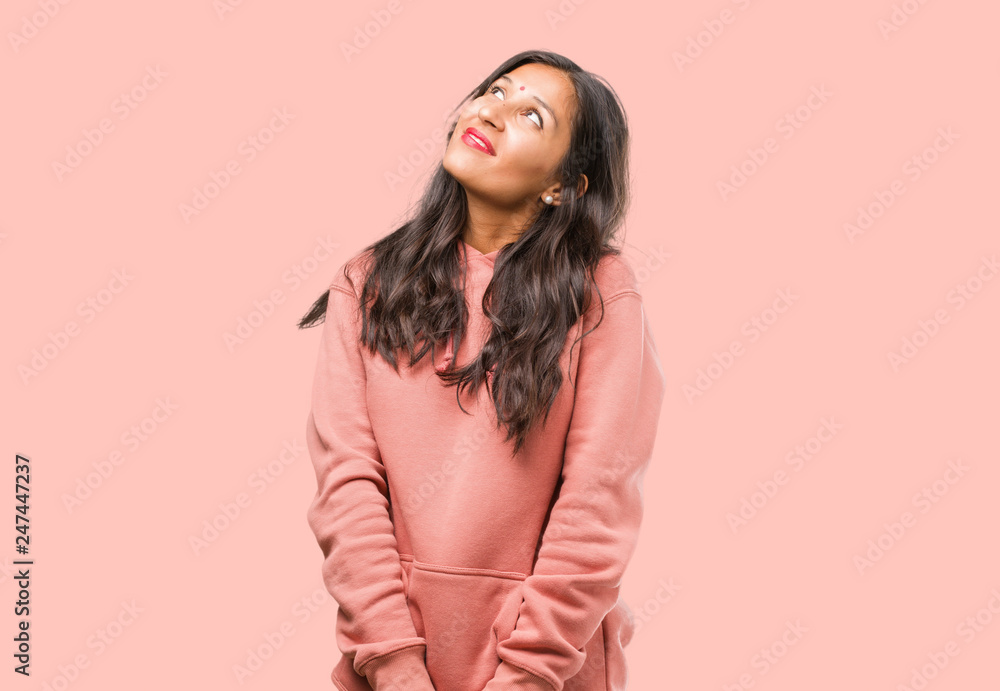 Portrait of fitness young indian woman looking up, thinking of something fun and having an idea, concept of imagination, happy and excited Portrait of fitness young indian woman looking up, thinking of something fun and having an idea, concept of imagination, happy and excited