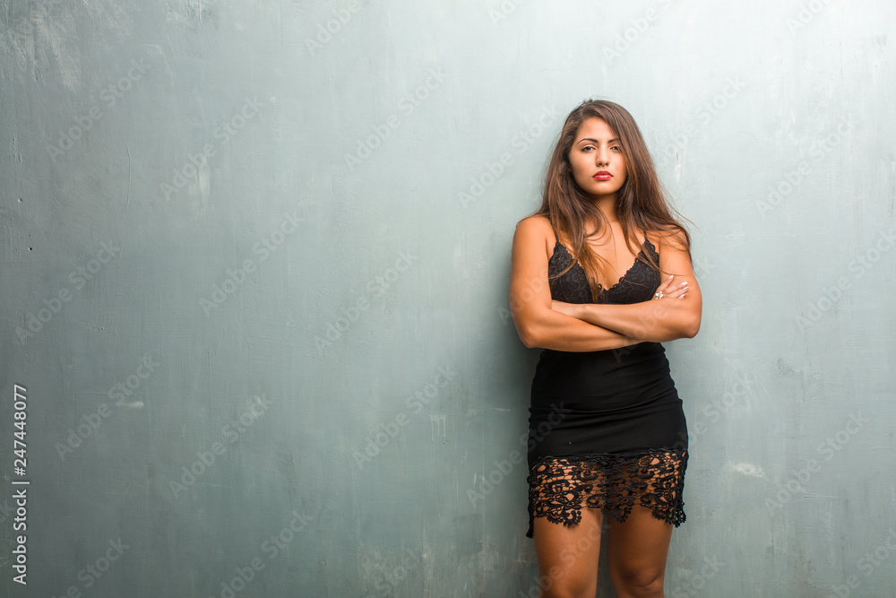Portrait of young pretty woman wearing a dress against a wall very angry and upset, very tense, screaming furious, negative and crazy Portrait of young pretty woman wearing a dress against a wall very angry and upset, very tense, screaming furious, negative and crazy