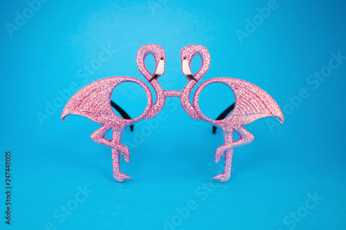 Flamingo sunglasses isolated on bright blue background. Minimal summer concept.