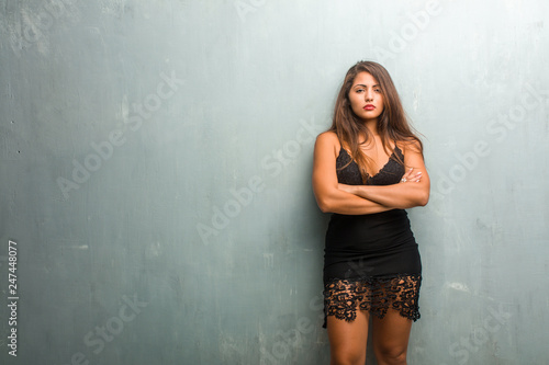 Portrait of young pretty woman wearing a dress against a wall very angry and upset  very tense  screaming furious  negative and crazy