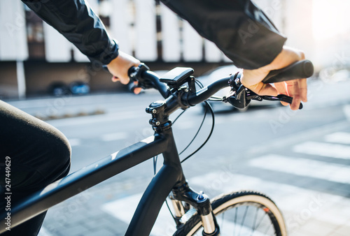 A midsection of businessman commuter with electric bicycle traveling to work in city. photo