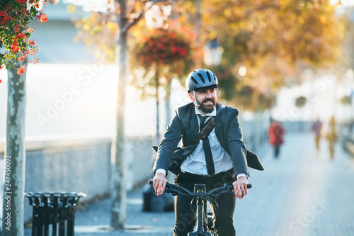 Fototapeta Hipster businessman commuter with electric bicycle traveling home from work in city