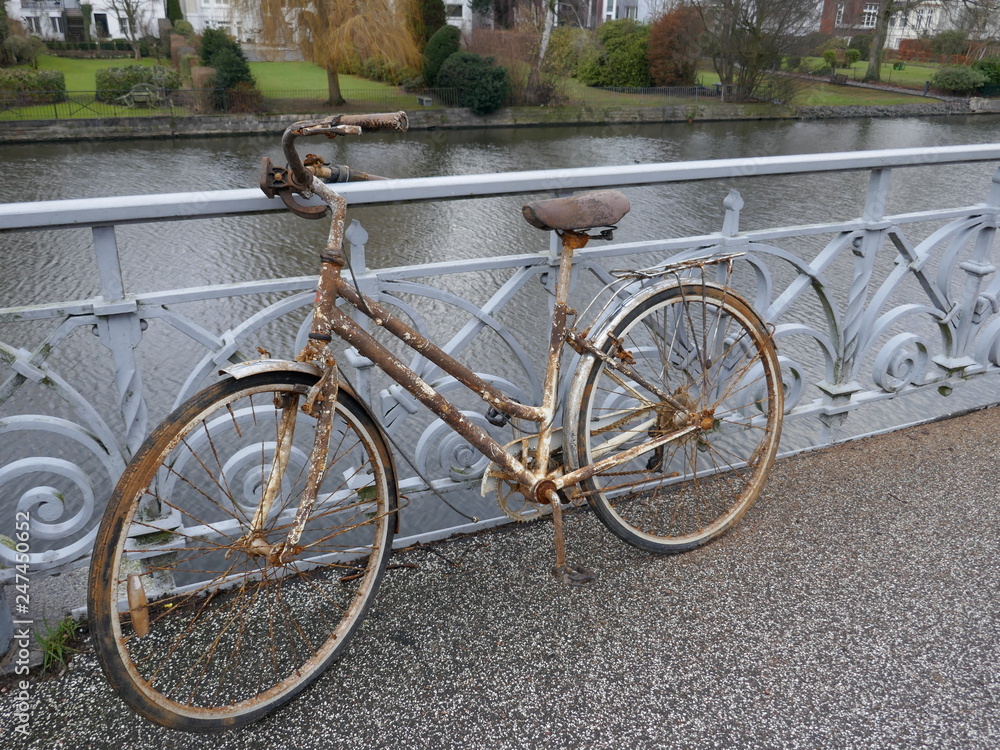Old rusty lady's bicycle, parked at a bridge railing and then forgotten

