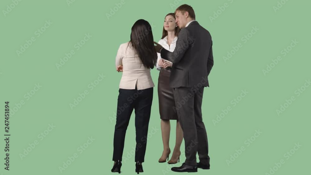 Male and two young women in office clothes are standing and looking at something. Green screen background