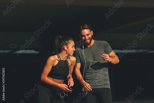 Young sports couple making break and listening to music and laughing
