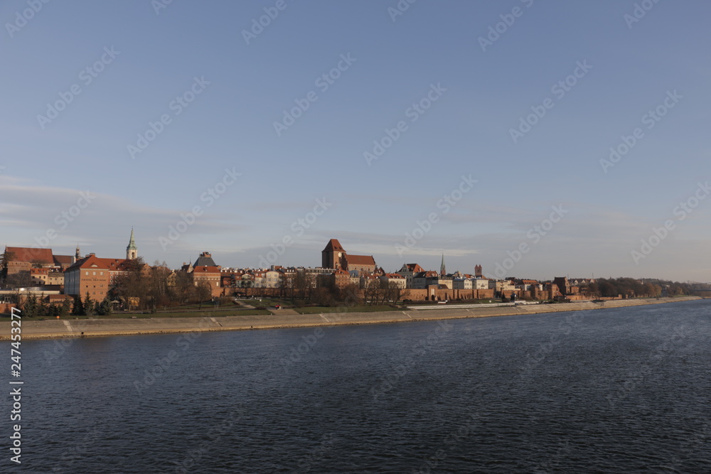 View of Torun from the bridge. In the foreground the river. In the background, the Vistula embankment, medieval defensive walls, the Old Town, the New Town, the Teutonic Castle, historic buildings.