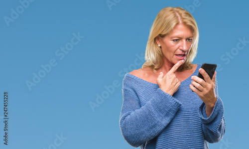 Middle age blonde woman sending message using smartphone over isolated background serious face thinking about question, very confused idea