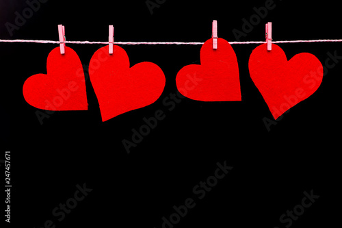 Red felt hearts on a rope. Handmade blank for greeting card, copy space, isolate on black background.