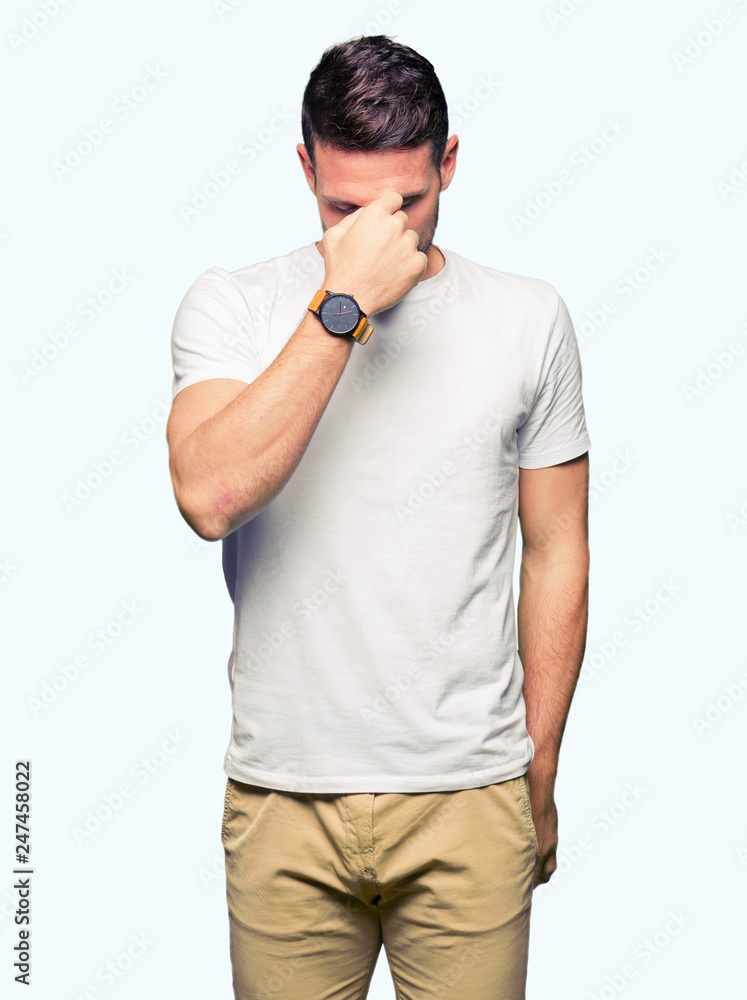 Handsome man wearing casual white t-shirt tired rubbing nose and eyes feeling fatigue and headache. Stress and frustration concept. Handsome man wearing casual white t-shirt tired rubbing nose and eyes feeling fatigue and headache. Stress and frustration concept.