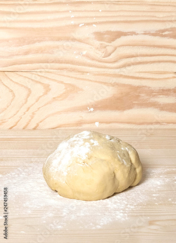 Homemade dough with flour on wooden background. Dough on the background with a place for copispeysa. Homemade cakes, bread, dumplings, dumplings