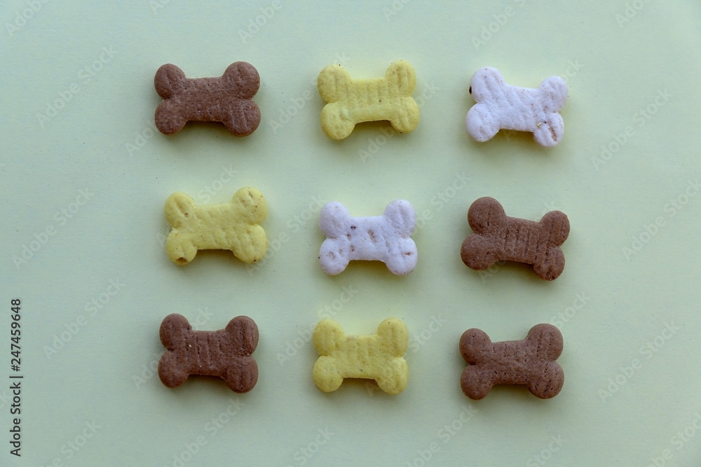 Obraz premium Dog treats, shaped like small bones, arranged on a pastel green background. 