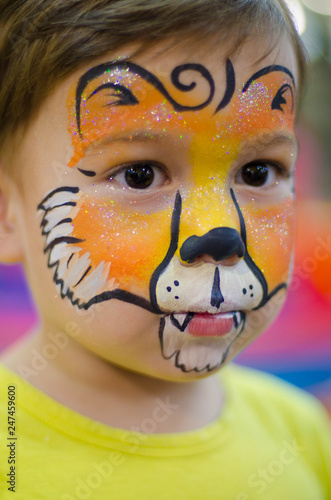 Fototapeta Naklejka Na Ścianę i Meble -  Cute boy with a face painted as a lion at birthday party