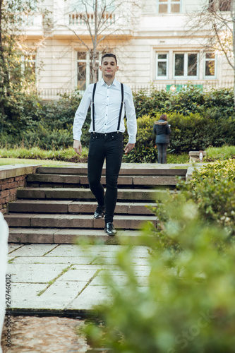 Man with white shirt and suspenders walking down stairs