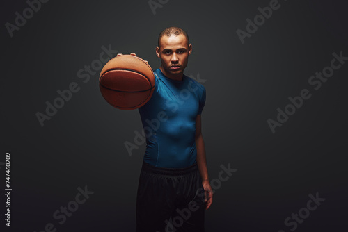 Keep it up. Handsome sportsman standing over dark background with basketball ball in his hand