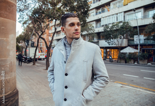 Portrait of businessman posing with gray coat in green park