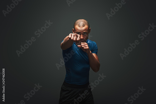 New champion. Muscular boxer is ready to fight. Young sportsman standing over dark background