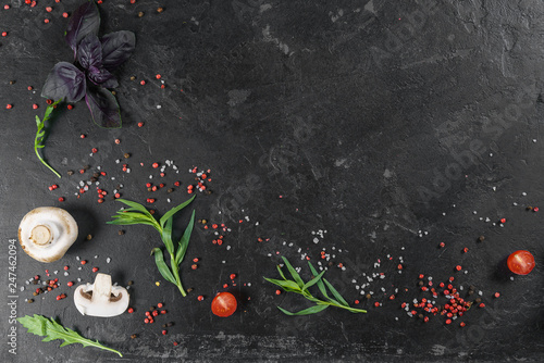 Selection of spices herbs and greens. Ingredients for cooking. Food background on black slate table. Top view copy space.