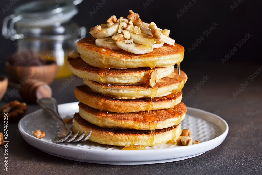 Homemade, hot pancakes with banana, honey and nuts on the kitchen table. Homemade, hot pancakes with banana, honey and nuts on the kitchen table.