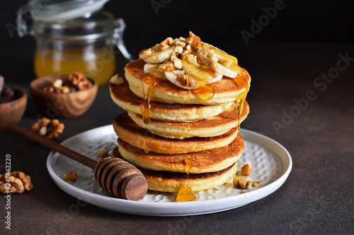 Homemade, hot pancakes with banana, honey and nuts on the kitchen table.